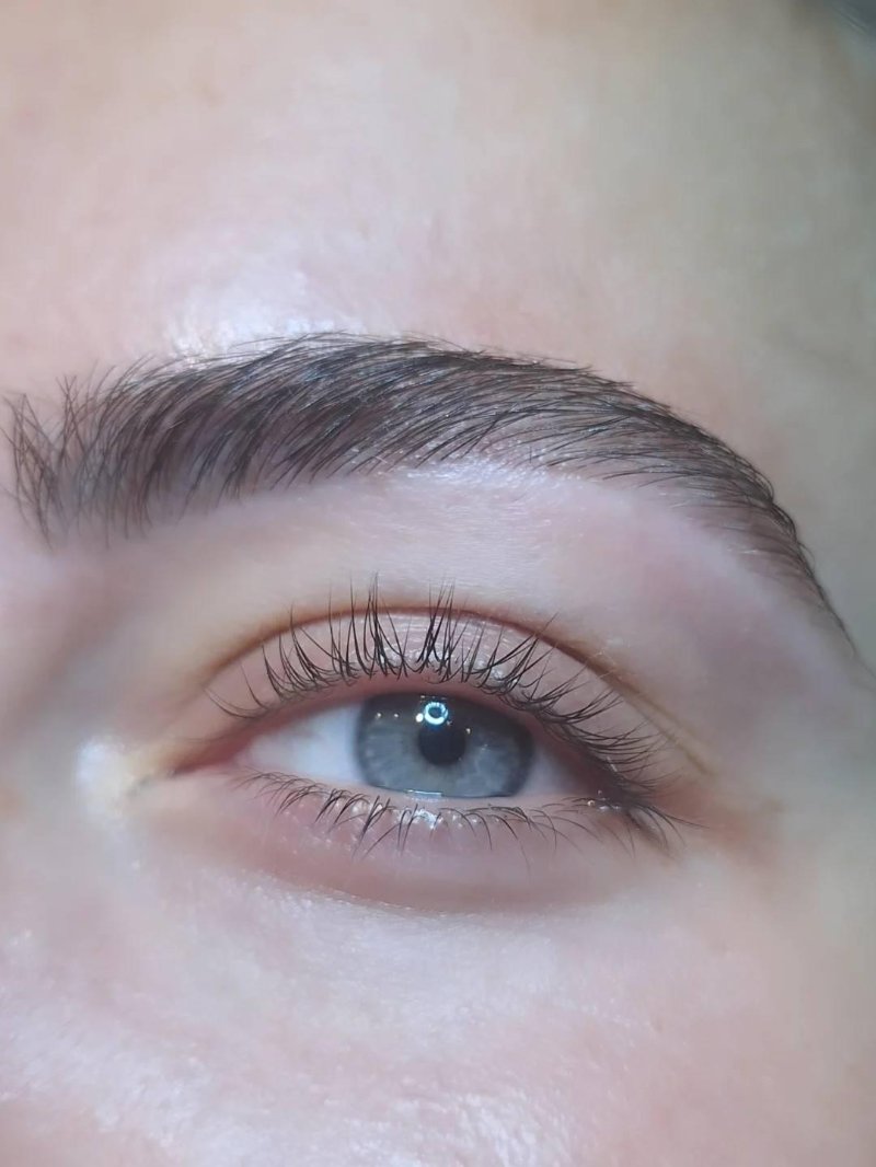 Gemodelleerde wenkbrauw boven een blauw oog, van dichtbij